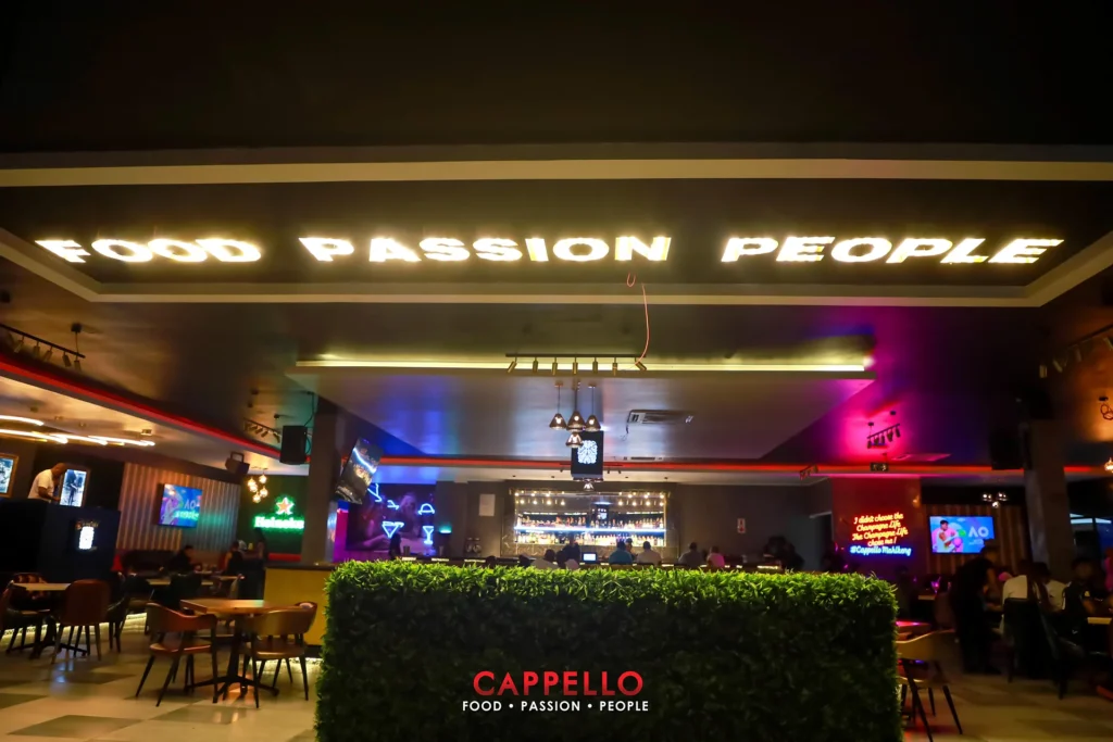 Cappello interior with illuminated signage, dining tables and evening lighting.