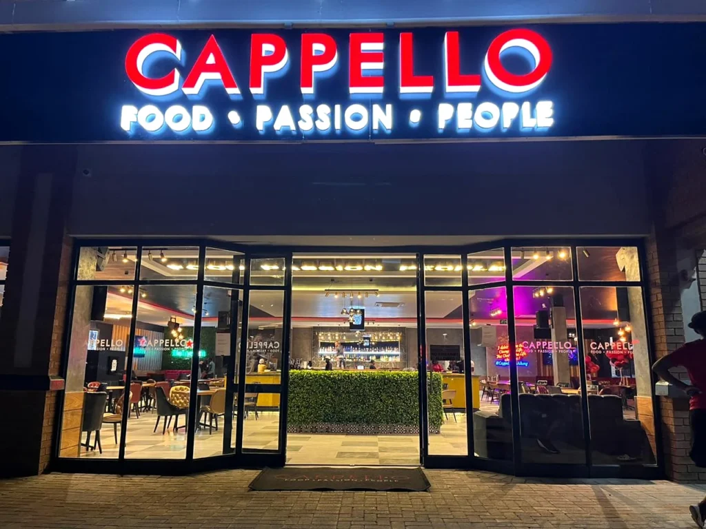 The illuminated Cappello entrance and glass doors at night.